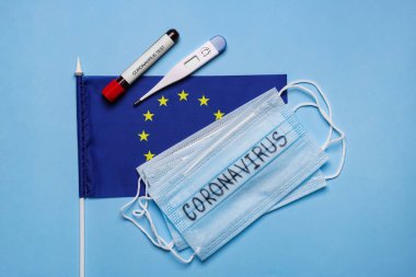 Avrupa Birliği bayrağı, koruyucu maskeler, termometre ve üzerinde açık mavi arka planda kan örneği bulunan test tüpü, düz. Coronavirüs salgını