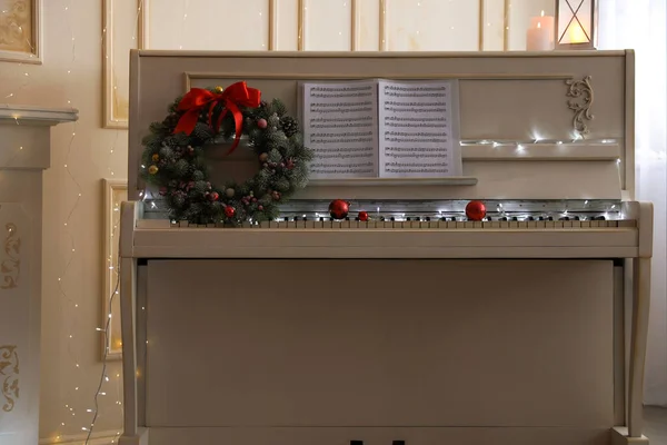 Біле Фортепіано Красивим Різдвяним Вінком Музичними Листами Приміщенні — стокове фото