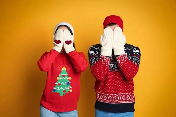 Pareja Suéteres Navidad Mitones Punto Sombreros Ocultando Caras Sobre Fondo —  Fotos de Stock