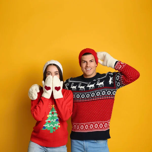 Pareja Suéteres Navidad Mitones Sombreros Punto Sobre Fondo Amarillo —  Fotos de Stock