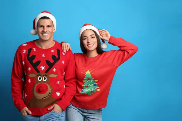 Pareja Suéteres Navidad Sombreros Santa Sobre Fondo Azul Espacio Para —  Fotos de Stock