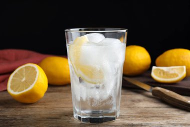 Limon dilimli soda ve ahşap masada buz.
