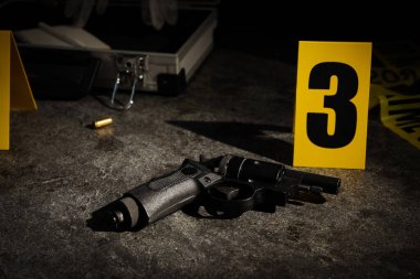 Mermi kovanı, silah ve suç mahalli işareti gri taş masada.