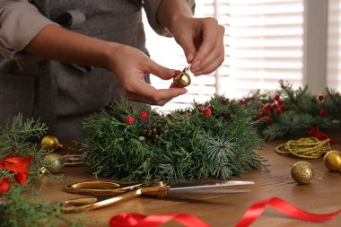 Çiçekçi, ahşap masada güzel Noel çelengi yapıyor, yakın plan.