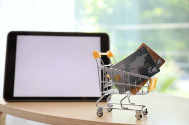 İnternet alışverişi. Modern tabletin yanında kredi kartı olan küçük bir araba.