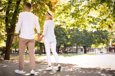 Mutlu çift yaz günü parkta yürüyor.