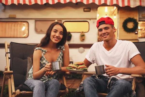 快乐的一对夫妇 带着汉堡包和杯子在拖车旁休息 野营季节 — 图库照片