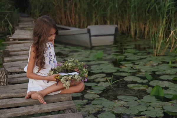 Menina Bonito Segurando Grinalda Feita Flores Bonitas Cais Perto Lagoa — Fotografia de Stock