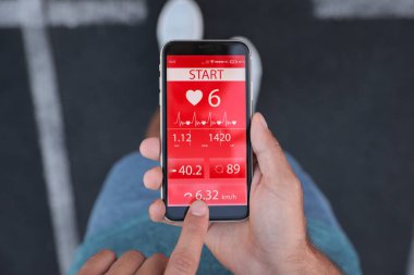Stadyumdaki akıllı telefondan spor uygulaması kullanan bir adam.
