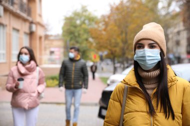 Sağlık maskeli genç bir kadın dışarıda yürüyor. COVID-19 salgını sırasında kişisel koruma