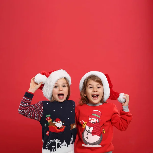 Дети Рождественских Свитерах Шляпах Санты Красном Фоне — стоковое фото