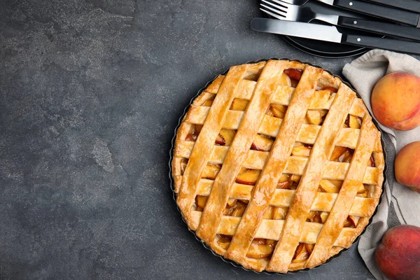 Delicious peach pie and fresh fruits on grey table, flat lay. Space for text