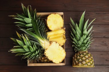 Tahta masadaki sandıkta ananas dilimleri düzdü.