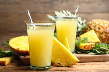 Lezzetli ananas suyu ve ahşap masada taze meyve.
