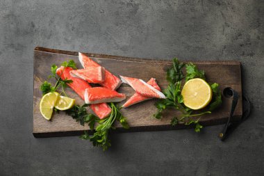 Gri masada yengeç çubukları, limon ve maydanoz, üst manzara.