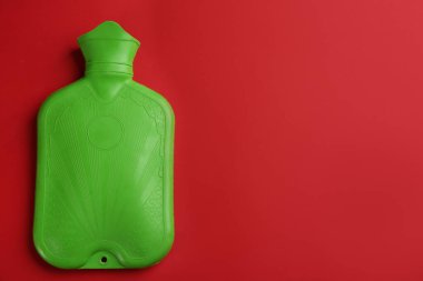 Kırmızı arka planda yeşil kauçuk su şişesi, üst manzara. Metin için boşluk