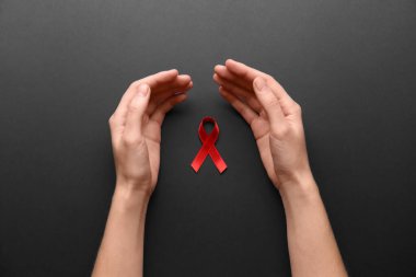 Siyah arka planda kırmızı farkındalık kurdelesi olan bir kadın. Dünya AIDS Hastalıkları Günü