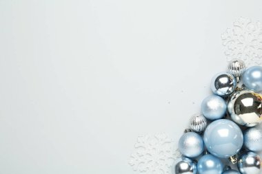 Işık arkaplanı üzerinde Noel topları ve dekor olan düz bir kompozisyon, metin için boşluk