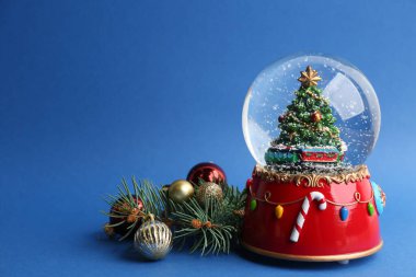 Güzel kar küresi, Noel baloları ve mavi arka planda köknar dalları, metin için alan