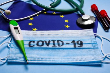 Avrupa Birliği bayrağı, koruyucu maskeler ve açık mavi arka planda tıbbi eşyalar. Coronavirüs salgını