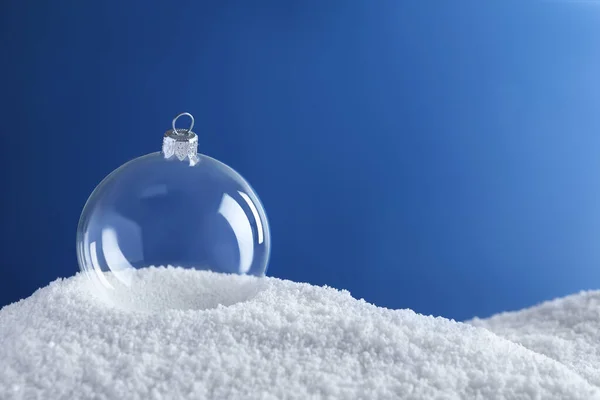 青い背景に雪の上に透明なクリスマスボール テキストのためのスペース — ストック写真