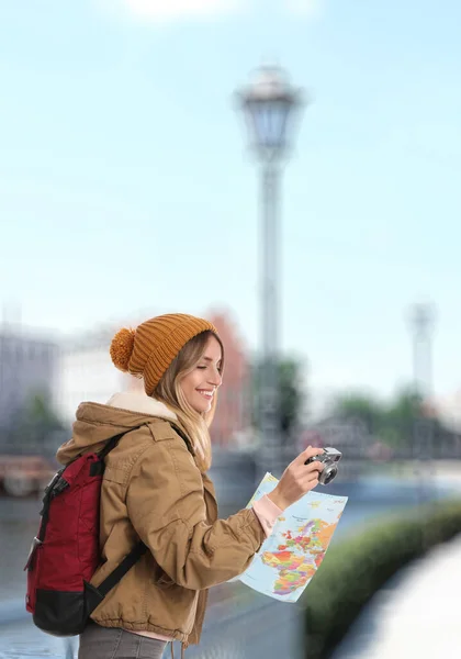 Happy traveler with camera and map in foreign city. Vacation trip
