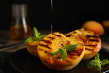 Lezzetli ızgara şeftalilerin üzerine bal dök, yakından.