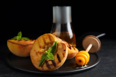 Lezzetli ızgara şeftali, bal ve naneli siyah masa.