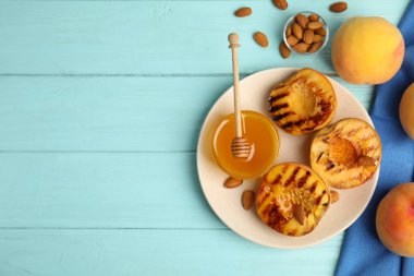Ballı ızgara şeftali ve açık mavi ahşap masada badem. Metin için boşluk