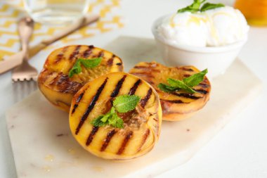 Lezzetli ızgara şeftali, ballı ve nane şekerli beyaz masa, yakın plan.