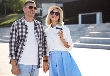 İçki içen mutlu çift yaz günü şehir caddesinde yürüyor.