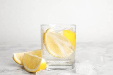 Limon dilimli soda ve beyaz mermer masada buz.
