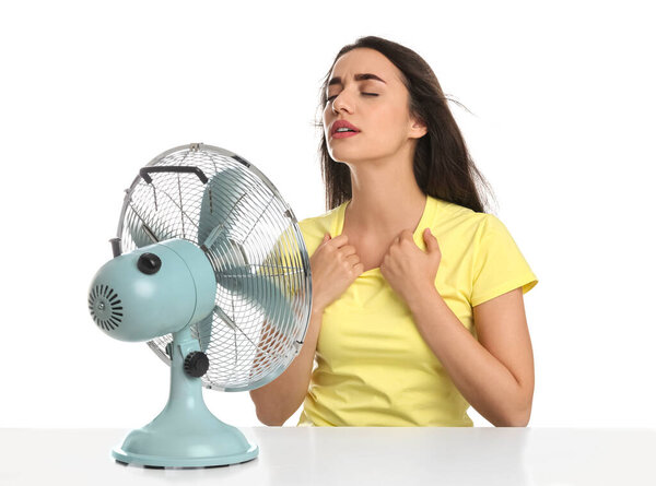 Женщина, страдающая от жары перед вентилятором на белом фоне. Летний сезон