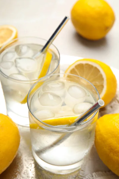 Soda water with lemon slices and ice cubes on table