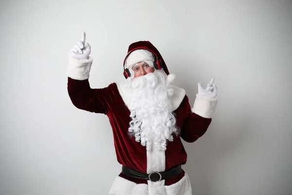 헤드폰을 크리스마스 음악을 가벼운 배경으로 산타클로스 — 스톡 사진
