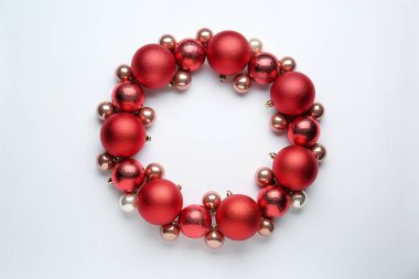 Beyaz arka planda kırmızı Noel toplarından yapılmış güzel bir çelenk.