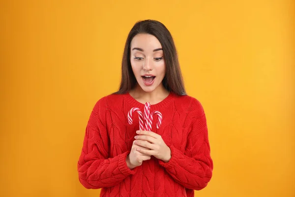 Mujer Joven Sorprendida Suéter Rojo Sosteniendo Bastones Caramelo Sobre Fondo — Foto de Stock