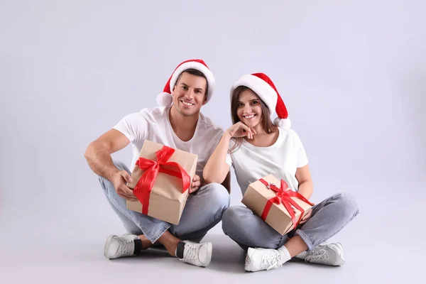 戴着圣诞礼帽 头戴浅色背景的年轻漂亮的夫妻 — 图库照片