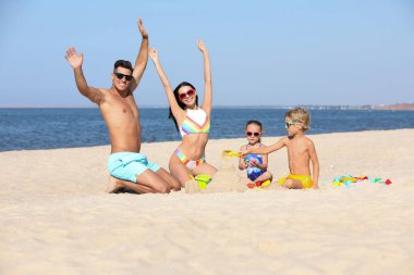 Mutlu bir aile deniz kenarındaki kumsalda oynuyor. Yaz tatili