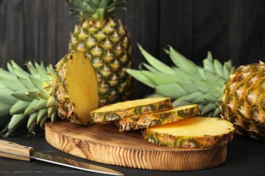 Siyah ahşap masada taze ananas kes.
