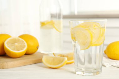 Limon dilimli soda ve mutfaktaki beyaz ahşap masada taze meyve. Metin için boşluk