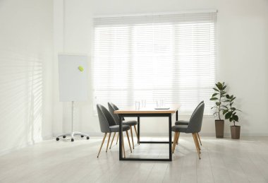 Konferans odasının içinde ahşap masa ve çizelge var.