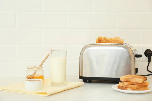Modern toaster and tasty breakfast on counter in kitchen