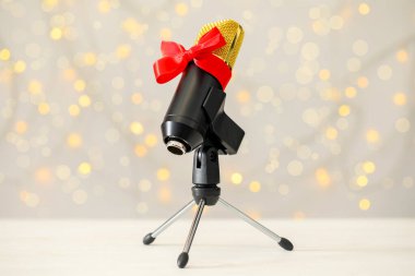 Bulanık ışıklara karşı kırmızı kurdeleli mikrofon. Noel müziği
