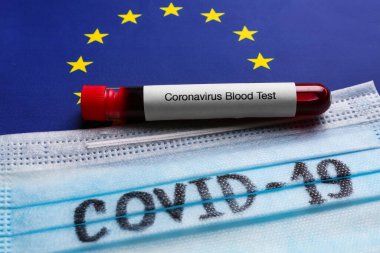 Avrupa Birliği bayraklarında kan örneği olan koruyucu maske ve test tüpü, yakın plan. Coronavirüs salgını