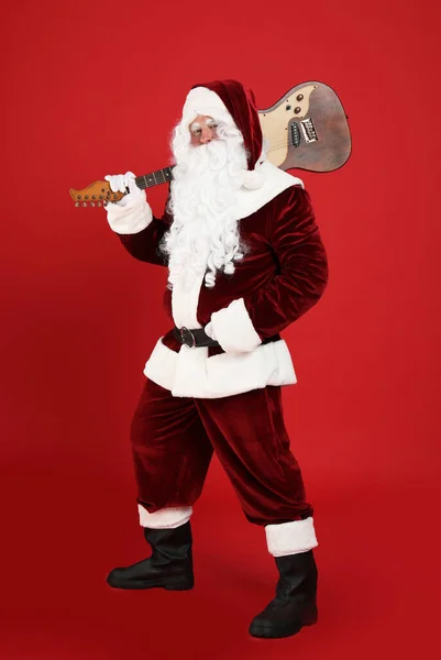 Święty Mikołaj Gitarą Elektryczną Czerwonym Tle Muzyka Świąteczna — Zdjęcie stockowe