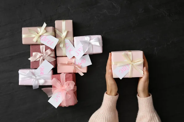 Kvinna Med Presentförpackning Vid Svart Bord Ovanifrån Adventskalender — Stockfoto