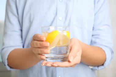 Elinde limon dilimleri ve buz küpleriyle bir bardak soda tutan kadın, yakın plan.