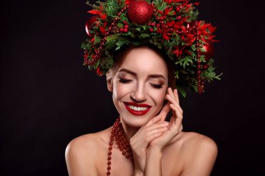 Siyah arka planda Noel çelengi giyen güzel genç bir kadın.