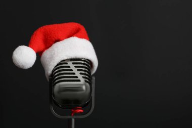 Siyah arka planda Noel Baba şapkası olan Retro mikrofon, mesaj için boşluk. Noel müziği
